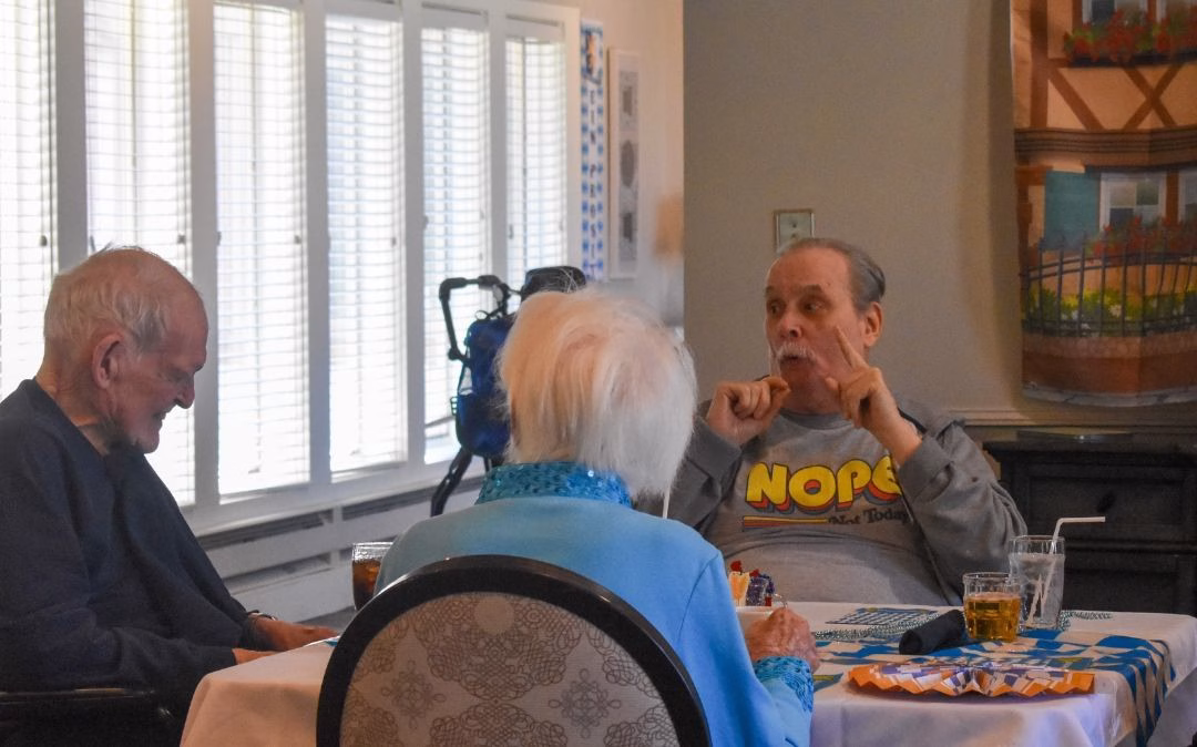 Friends share laughter and a meal at the Heritage dining room at Willow Brook Home in Columbus, Ohio, where social connection is part of the daily assisted living experience.